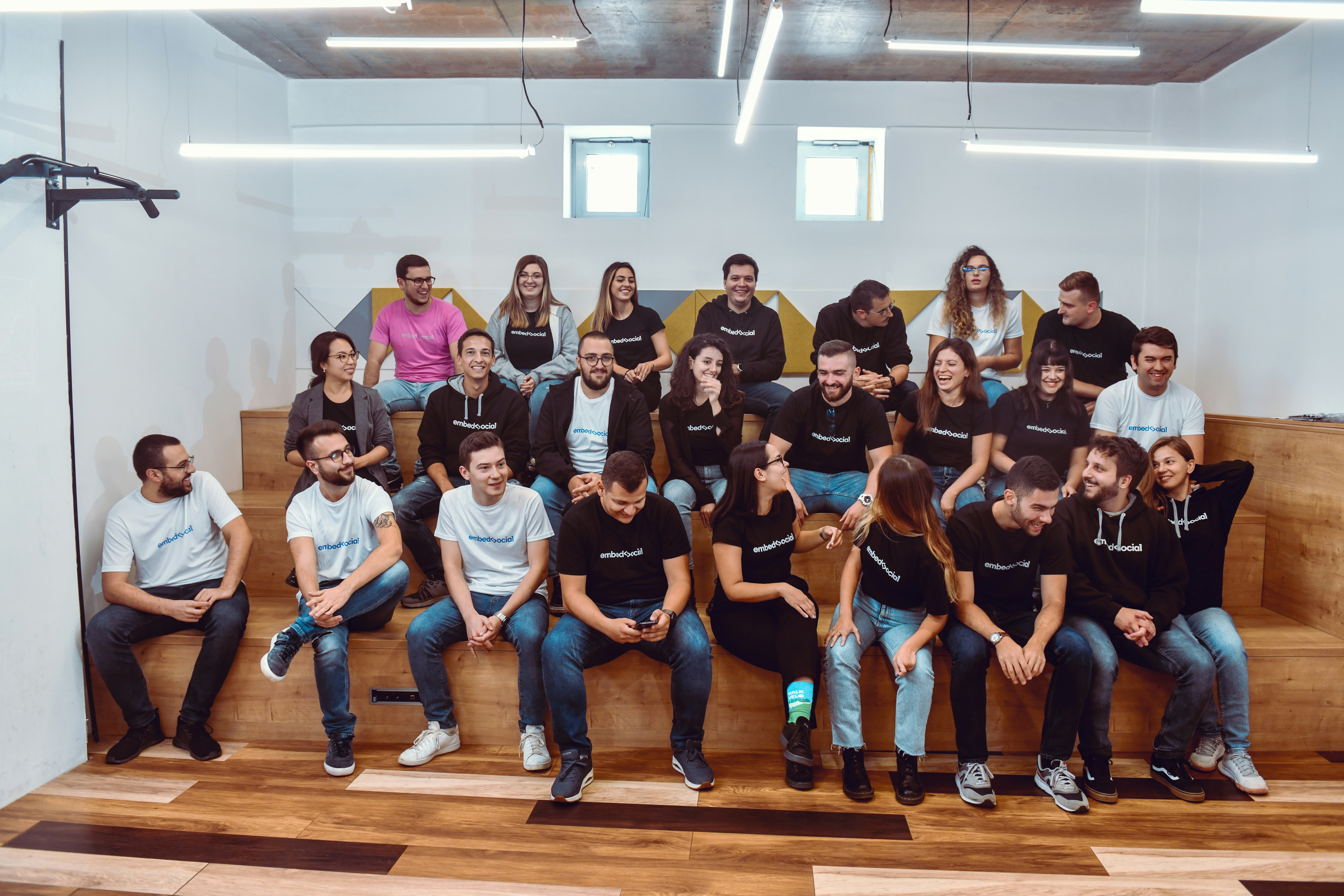 A large group of people seated in rows in an auditorium, many wearing EmbedSocial shirts.